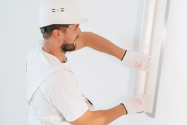A worker installing plasterboard inside a building