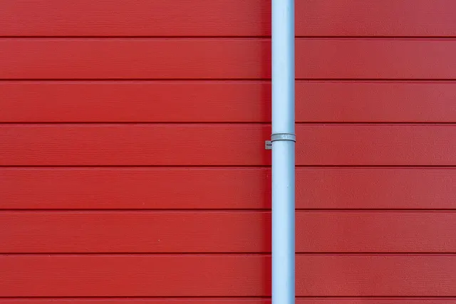 A white downpipe against a red exterior wall