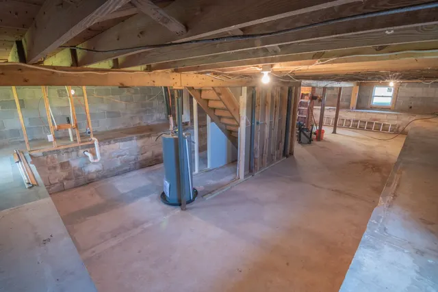 Unfinished basement with exposed beams and utility pipes